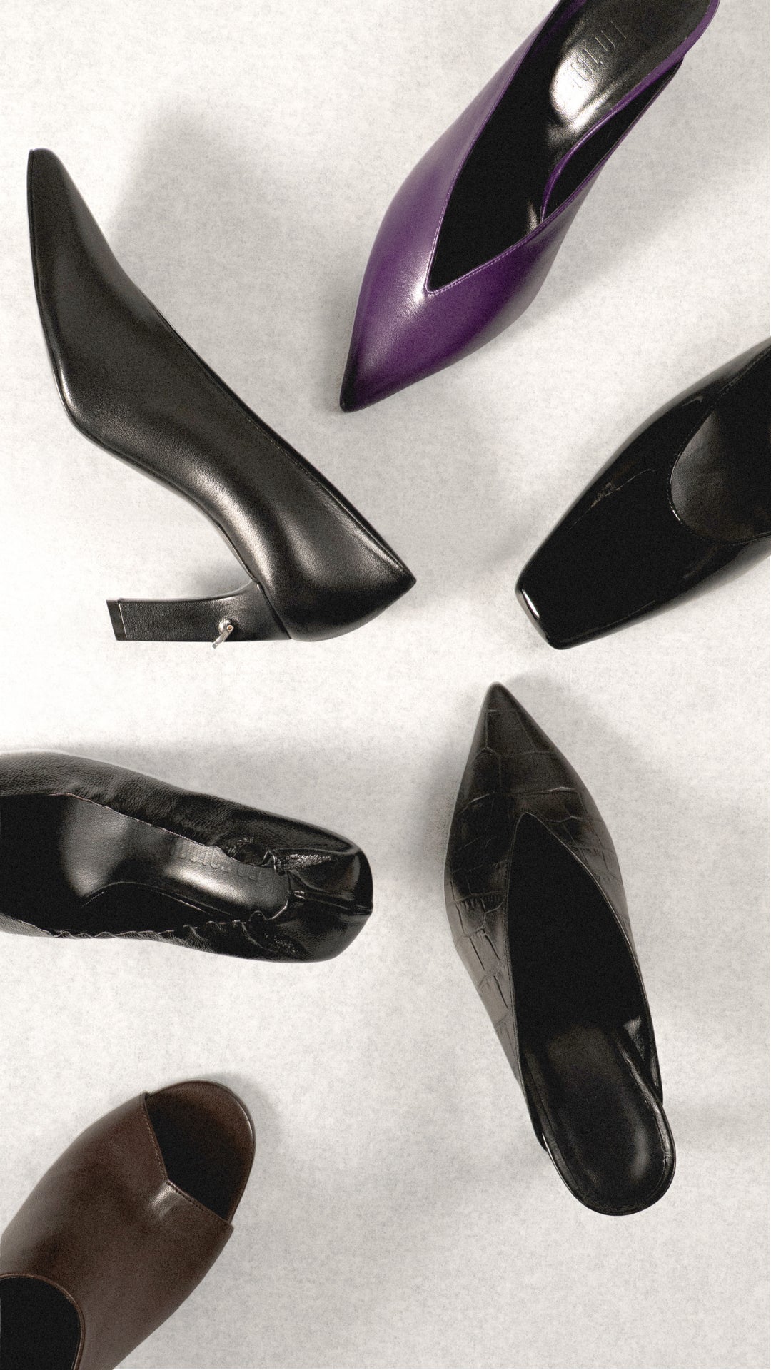 Black, purple and brown high-heeled shoes arranged on a neutral background