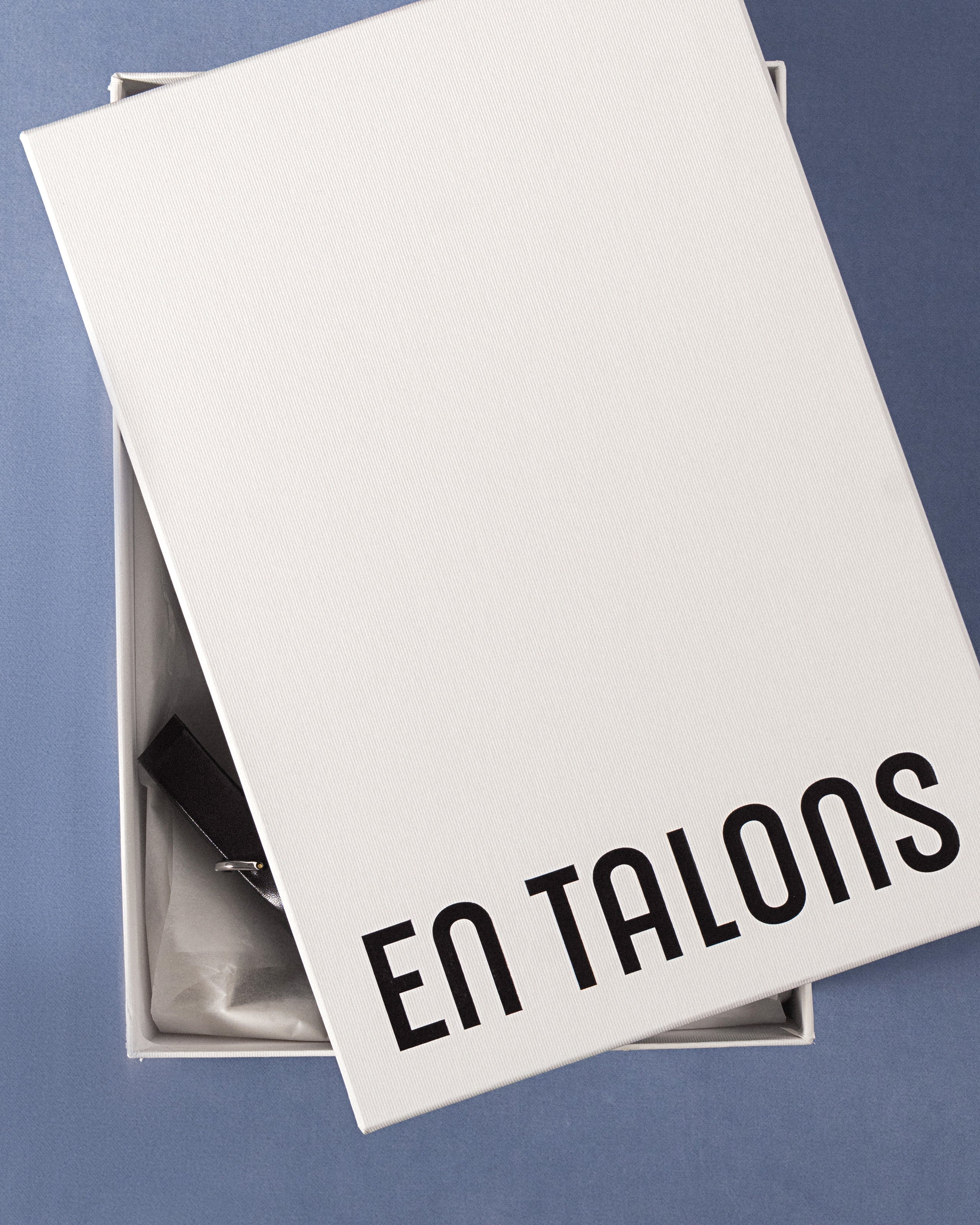 White box with 'EN TALONS' logo printed on a blue background